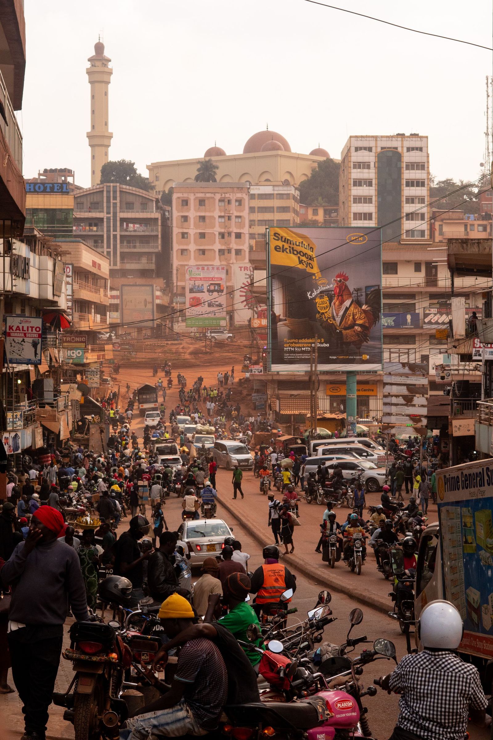 A busy street in central Kampala with motorbikes and a minaret behind