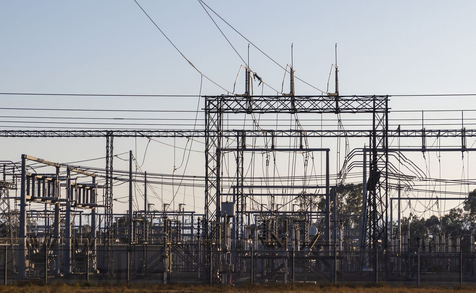 A high-voltage substation with steel structures and power lines at dawn